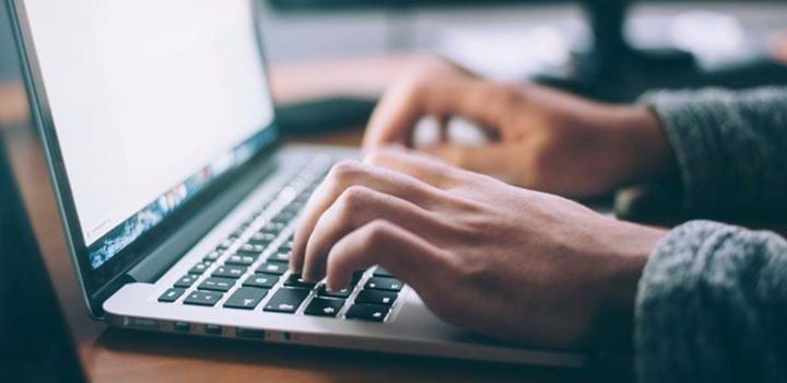 A close up of a person typing on a laptop keaboard.