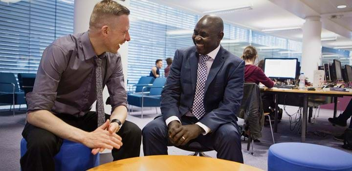 Office environment - two males smiling and chatting